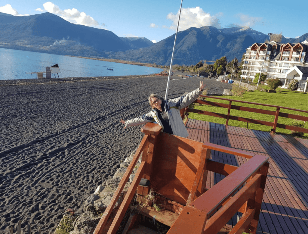 Lago Villarica com praia de areia vulcânica preta e céu claro em Pucón, Chile.