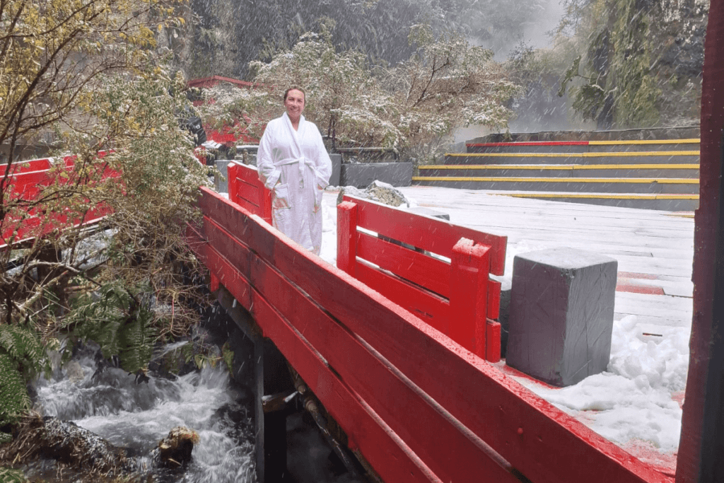 Pessoa do grupo de roupão caminhando pelas passarelas das Termas Geométricas em direção às piscinas, no Parque Nacional Villarrica, Patagônia Chilena.