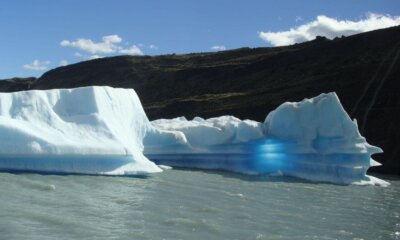 Grande bloco de gelo com formato interessante flutuando no Lago Argentino, refletindo tons de branco e azul conforme o sol incide sobre sua superfície.