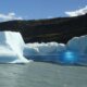 Grande bloco de gelo com formato interessante flutuando no Lago Argentino, refletindo tons de branco e azul conforme o sol incide sobre sua superfície.