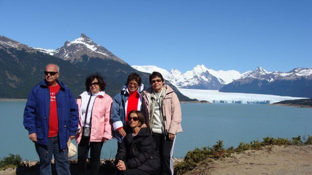 Entrada principal do Parque Nacional Los Glaciares com vista para o Glaciar Perito Moreno ao fundo, destacando o contraste entre a vegetação e o gelo imponente.