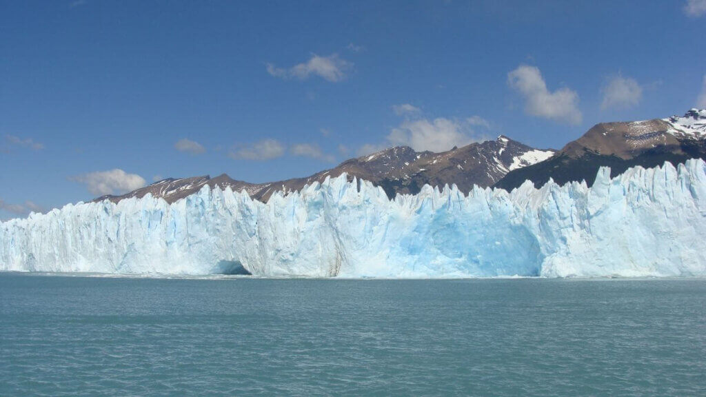 Vista do Glaciar Perito Moreno a partir do Braço Norte do Lago Argentino, com suas impressionantes paredes de gelo e águas azul-turquesa ao redor.