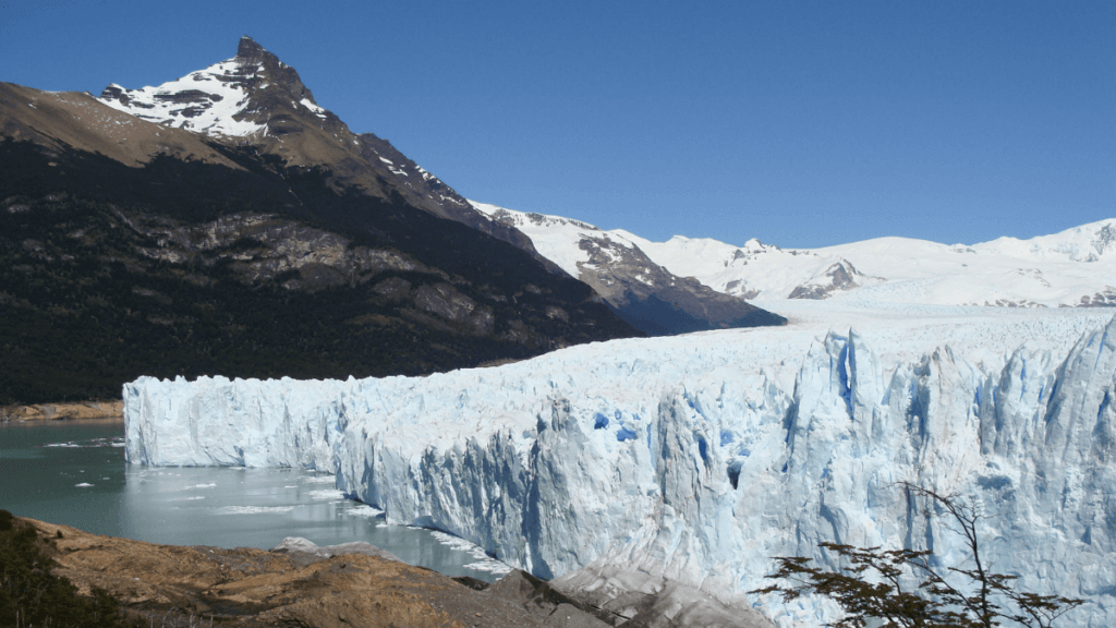 Vista lateral do Glaciar Perito Moreno, destacando suas imponentes paredes de gelo que se projetam sobre o Lago Argentino, criando um contraste impressionante.