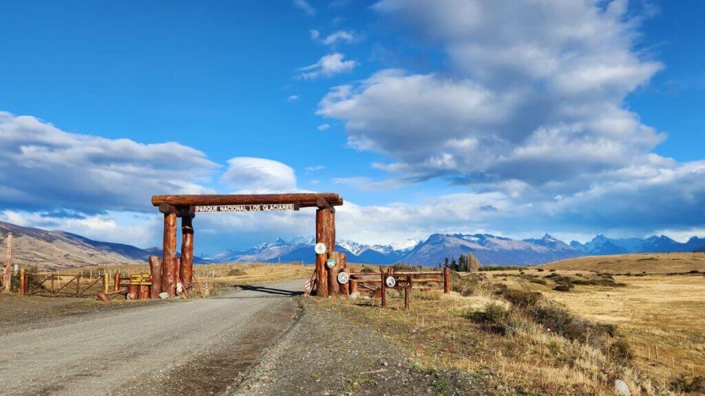 Entrada do Parque Nacional Los Glaciares com estrada de rípio e vegetação patagônica ao redor, destacando a paisagem típica da região