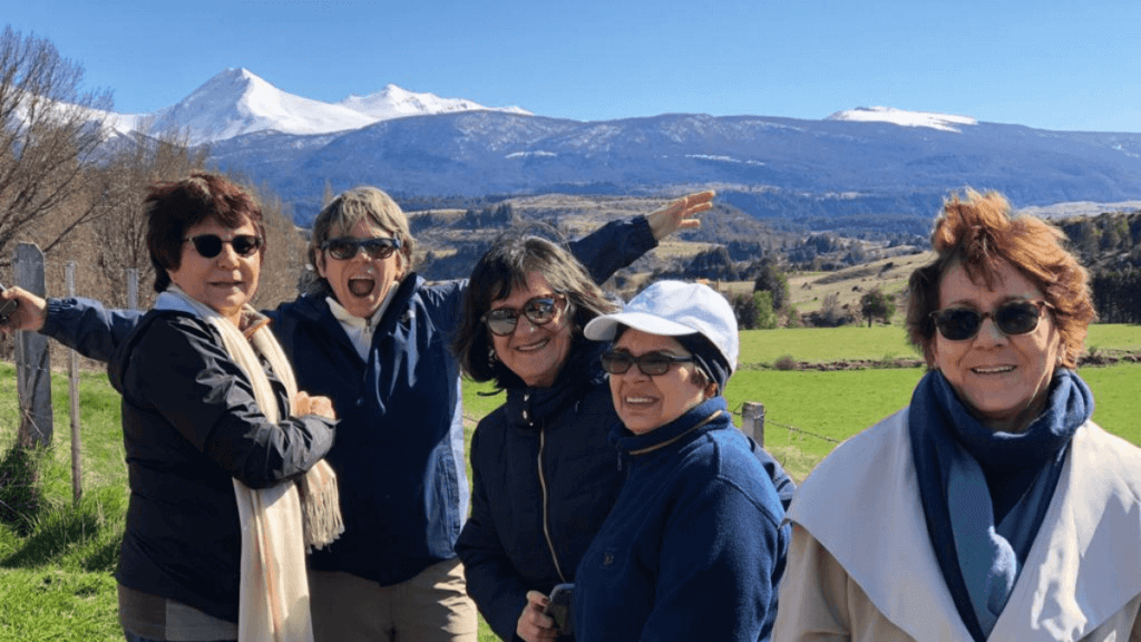 Campos verdesjantes em Aysén com montanhas nevadas ao fundo, compondo uma paisagem que mistura tranquilidade e grandiosidade na Patagônia Chilena.