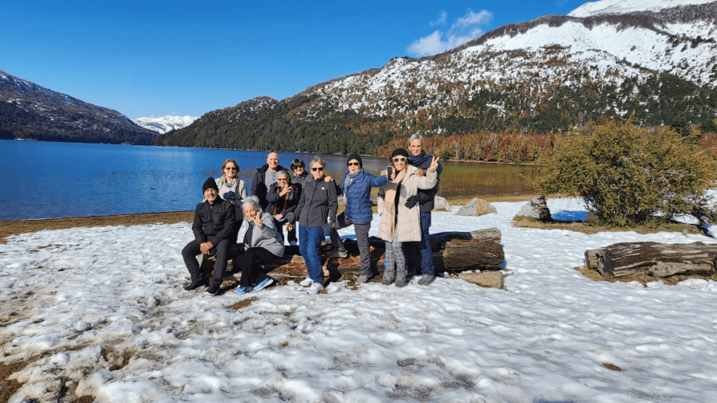 Grupo reunido na margem do lago ao longo do Caminho dos 7 Lagos, rodeado por montanhas e vegetação nativa na Patagônia Argentina.