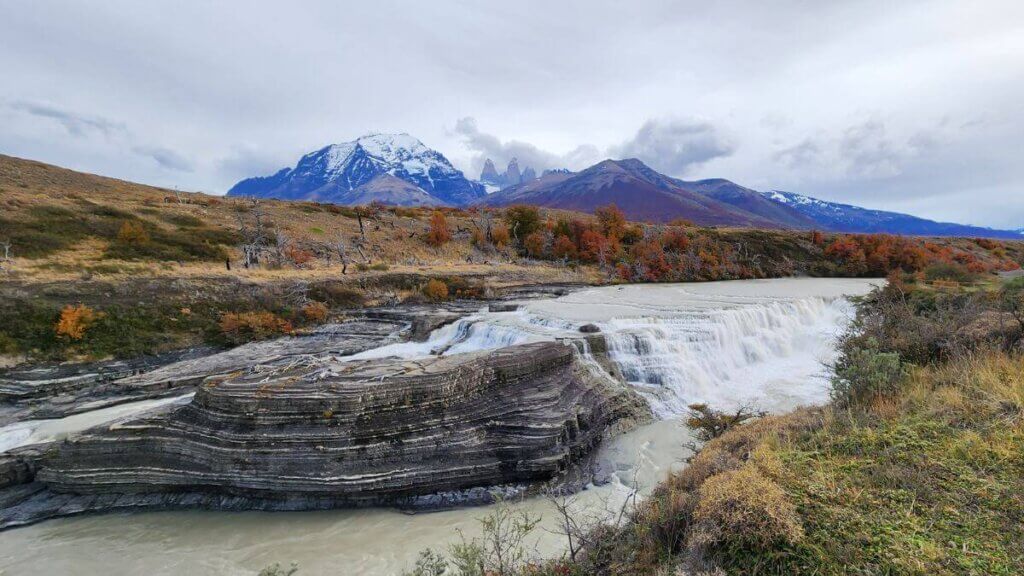 Cascada Río Paine com vegetação em tons outonais ao redor, no Parque Nacional Torres del Paine, Patagônia Chilena