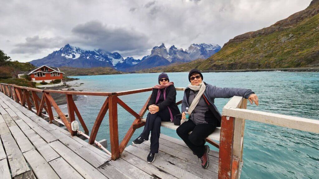 Vista da ponte que leva à Hostería Pehoé, com o Lago Pehoé em primeiro plano, a pequena construção vermelha à beira do lago e os Cuernos del Paine ao fundo