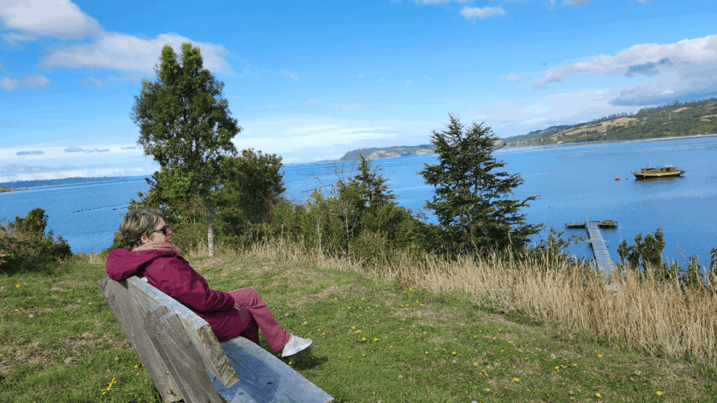 Vista do mar interior de Chiloé em dia de céu azul, mostrando águas tranquilas em tons azul-esverdeados que refletem a luminosidade solar, capturando um momento raro de claridade na paisagem marítima do arquipélago.