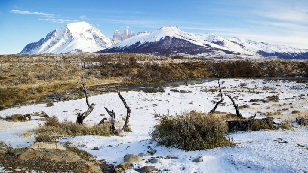 Paisagem de inverno no Parque Nacional Torres del Paine com neve cobrindo o solo e as Torres del Paine ao fundo