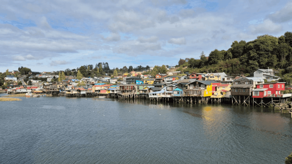 Palafitas coloridas da Gamboa em Castro, Chiloé, refletidas nas águas durante a maré cheia.