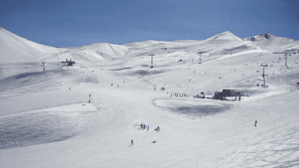 Esquiadores descendo as pistas de Valle Nevado em plena temporada de inverno, com neve bem distribuída pelas encostas.