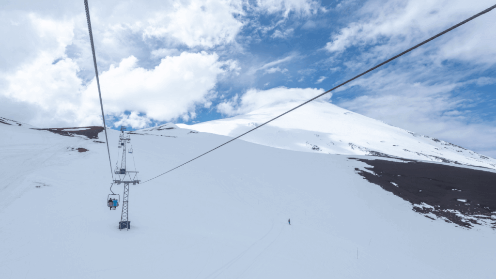 Teleférico subindo o Vulcão Osorno com encostas nevadas, a caminho da estação de esqui na Região dos Lagos, Chile.