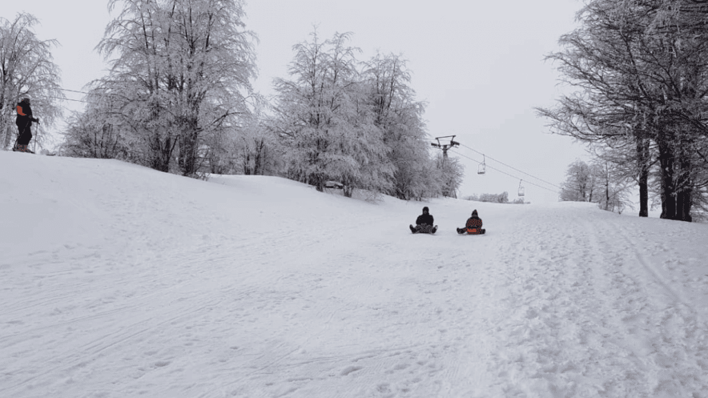 Descida de trenó na neve em Pucón, Chile, com paisagem de inverno ao redor da estação de esqui do Vulcão Villarrica.