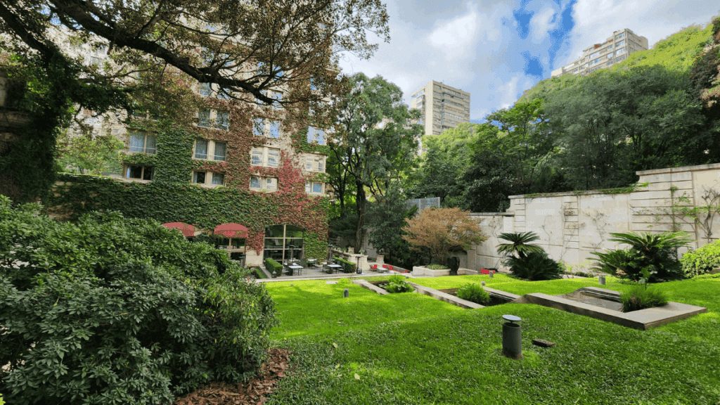 Jardim interno do Palácio Duhau, um dos Palácios de Buenos Aires, com caminhos elegantes, áreas verdes e integração entre arquitetura clássica e contemporânea.