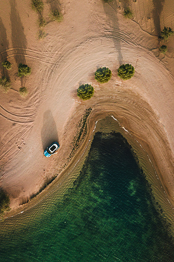 aerial-photography-of-vehicle-parked-on-beach-near-bushes-1443657